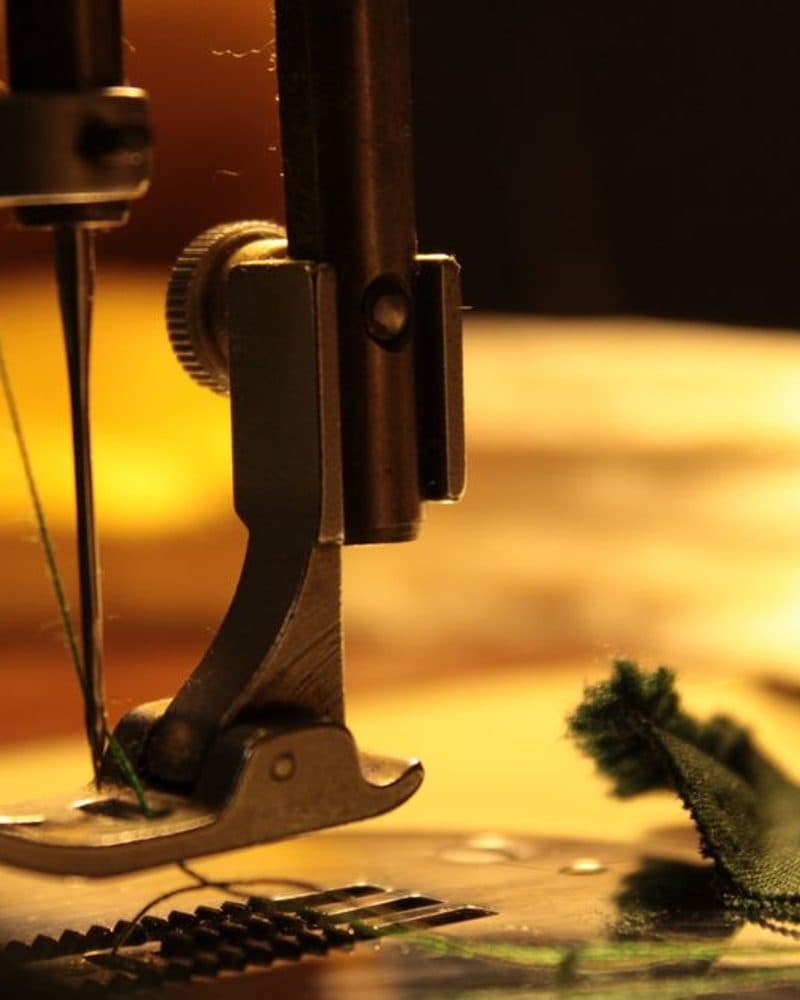 A sewing machine needle stitching fabric, close up