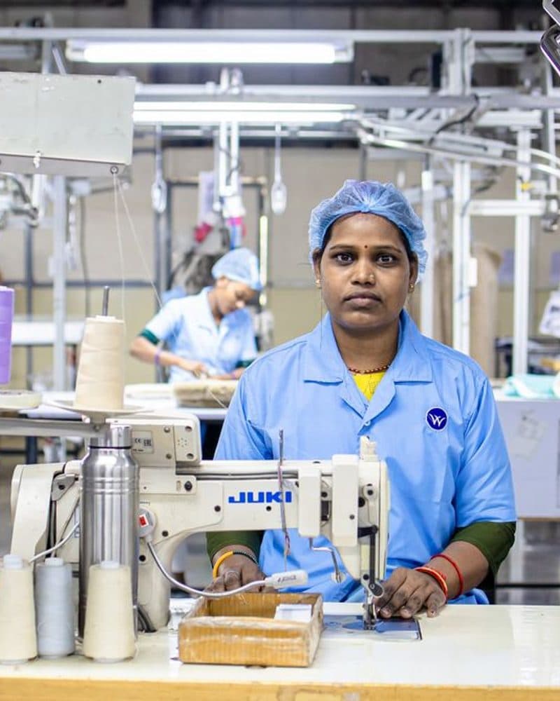 A worker sewing garments on a factory production line