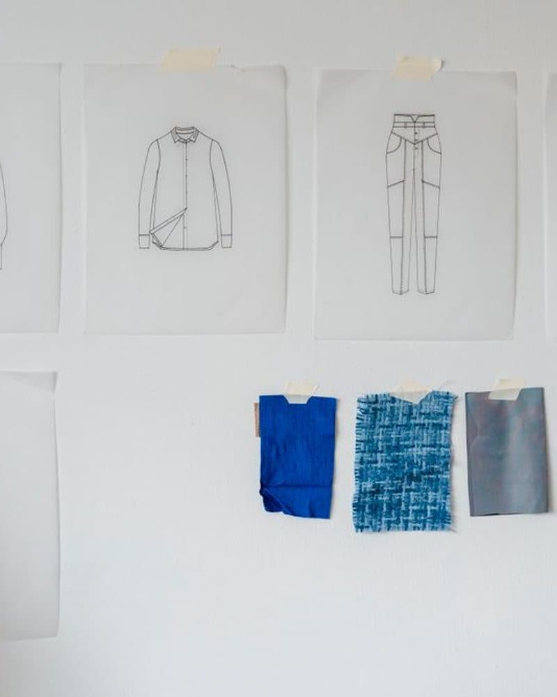 Fashion design sketches pinned up alongside small fabric swatches