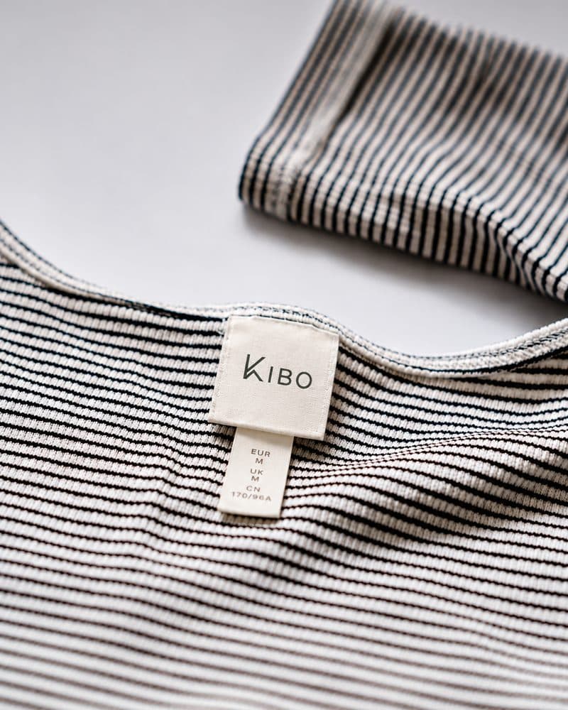 Close-up of a striped t-shirt's neck tag showing the KIBO logo
